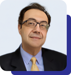 Professional headshot of a man in a dark suit, light blue shirt, and yellow tie, wearing glasses and a subtle smile.